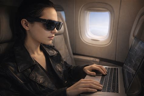 Passenger using XReal AR glasses with a laptop on a flight